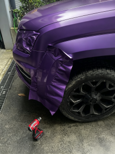 DIY TPU purple car wrap installation on SUV fender, heating vinyl film with cordless heat gun for proper edge wrapping, MOZXFILM high‑quality car wrapping film during installation process