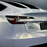 Rear taillight close-up Tesla Model 3 wrapped with MOZX White Iridescent Gold PET vinyl wrap, glossy white golden color shift trunk panel