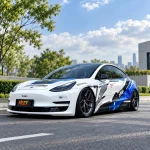 Tesla Model 3 white-blue-black racing livery wrap, lowered stance, city road