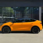 Full side profile Tesla Model Y wrapped with MOZX Easy McLaren Orange glossy PET vinyl wrap, seamless full body coverage