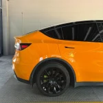 Full rear view Tesla Model Y wrapped MOZX Easy McLaren Orange glossy PET vinyl wrap, unified orange finish on trunk and rear bumper
