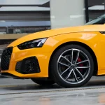 Close-up front fender & wheel detail Audi RS wrapped MOZX Smart McLaren Orange PET wrap, perfect conformity on sharp sport body curves