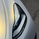 Close‑up MOZX Smart white iridescent gold PET car wrap texture by headlight