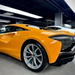 Rear side profile McLaren supercar wrapped MOZX Elite McLaren Orange TPU color wrap, uniform orange hue across rear fender & quarter pane