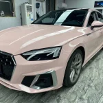 Close-up front fascia Audi A5 wrapped MOZX Smart Shell Pink PET vinyl wrap, seamless wrapping on bumper, headlight and wheel arch