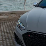 Macro shot Audi RS5 hood and matrix LED headlight with MOZX Elite Bernina Grey PET-TPU wrap, reflective composite film texture showing high-clarity gloss
