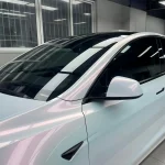 Close-up texture of MOZX Elite White Iridescent Red TPU wrap on Tesla Model Y body panel