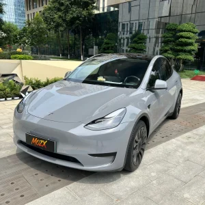 Tesla Model Y wrapped in MOZX Easy Nardo Grey high-gloss PET vinyl wrap, modern business plaza full front exterior shot