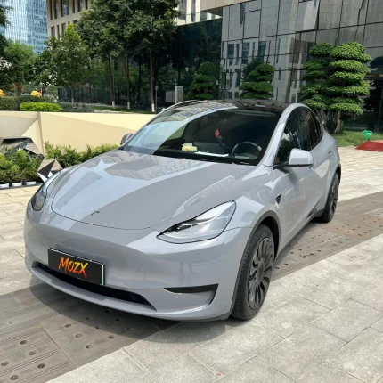 Tesla Model Y wrapped in MOZX Easy Nardo Grey high-gloss PET vinyl wrap, modern business plaza full front exterior shot