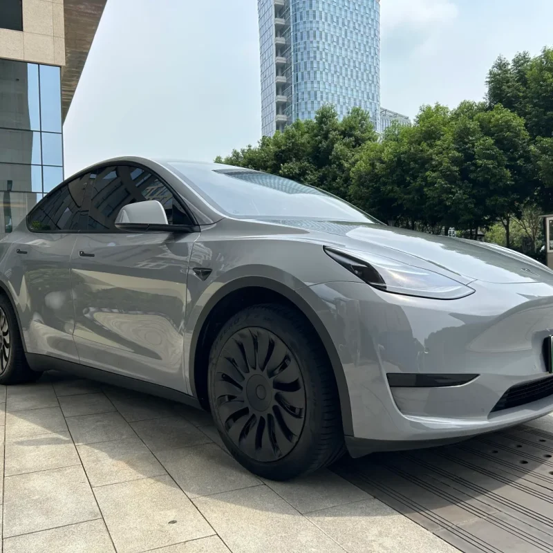 Side fender wheel arch close-up of Tesla Model Y wrapped MOZX Easy Nardo Grey glossy PET wrap, smooth uniform grey coverage on curved EV body panels